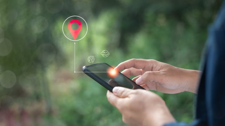 Close-up of a hand using a smartphone with a GPS location pin icon, representing mobile navigation, geolocation tracking, and real-time positioning in smart technology